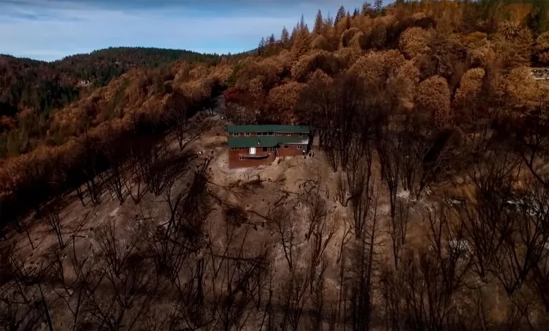 Steel-framed home standing after a fire beside wood-framed homes